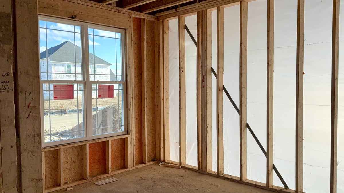 Residential construction interior with exposed wood framing and windows