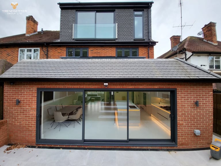 Modern brick extension with large black-framed sliding glass doors and contemporary interior visible inside