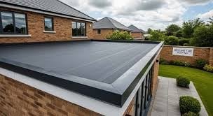 Modern flat roof extension with dark membrane on brick house, featuring manicured lawn and fence in background