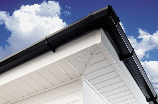 Close-up of white garage door with black trim under blue sky and white clouds