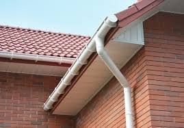 White gutter and downspout system installed on brick house with red tile roof