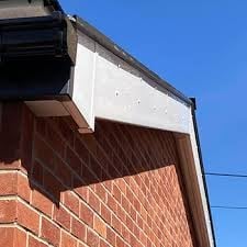 Exterior corner view of a brick building with a white and dark metal overhang or eave against a clear blue sky