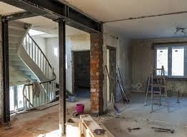 Interior construction site with metal staircase, exposed brick, and renovation work in progress