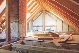 Interior of a residential construction site showing wooden framing, exposed beams, and an arched ceiling with natural light streaming in