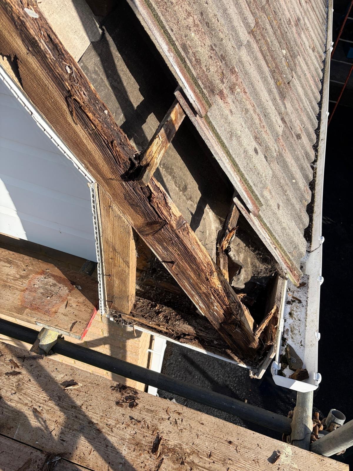 Damaged wood siding on a building corner showing rotted structural boards and exposed weathered wood framing